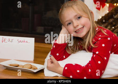 Adorable Schule Alter Mädchen mit Hinweis und Cookies Links für Santa für Weihnachten Stockfoto