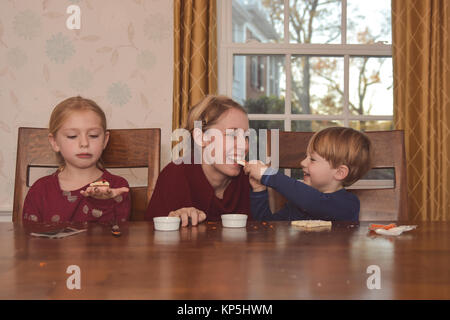 Mutter mit 2 Kinder dekorieren Kekse Stockfoto