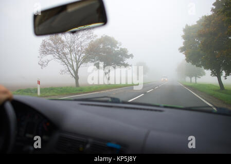 Auto fahren in dichtem Nebel, gesehen durch die Windschutzscheibe eines anderen Fahrzeugs Stockfoto