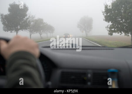 Auto fahren in dichtem Nebel, gesehen durch die Windschutzscheibe eines anderen Fahrzeugs Stockfoto