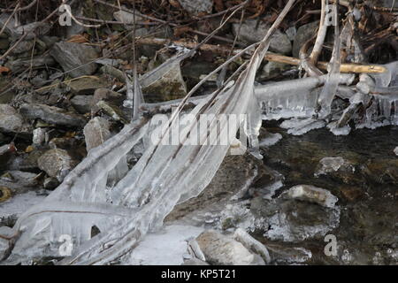 Vereisung auf Steinen und Ästen in der Nähe der Bank eines Cascading Wasserstraße mit dem Start der Wintersaison. Stockfoto