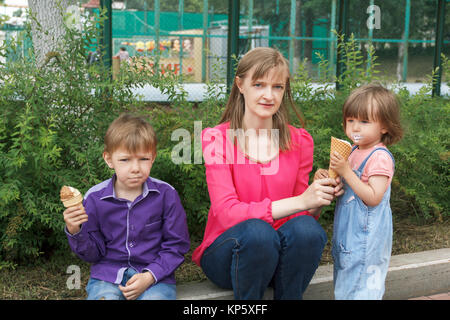 Mutter mit Jungen und Mädchen im Sommer Park essen Eis sitzen Stockfoto