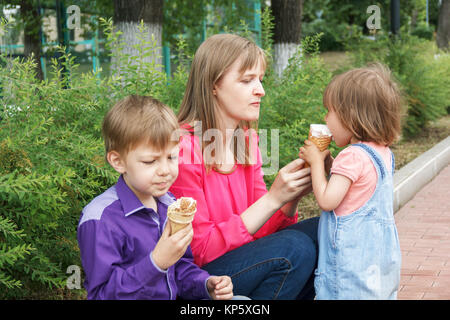 Mutter mit Jungen und Mädchen im Sommer Park essen Eis sitzen Stockfoto