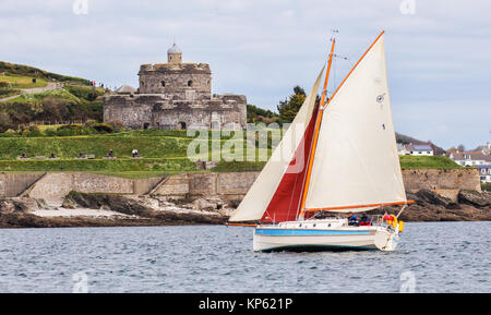 Kleine Yacht mit roten und weißen Segeln vorbei an St Mawes Castle auf der Roseland Halbinsel in Cornwall, Großbritannien Stockfoto