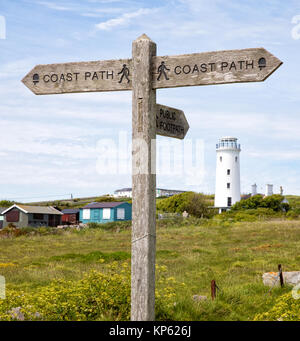 Coast Path waymarker auf dem South West Coast Path in Portland Bill mit dem alten Inland Leuchtturm und Strand Hütten in der Ferne - Dorset UK Stockfoto