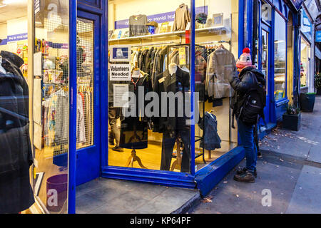 Frau Surfen im Fenster eines Charity Shop in Highgate, London, UK Stockfoto