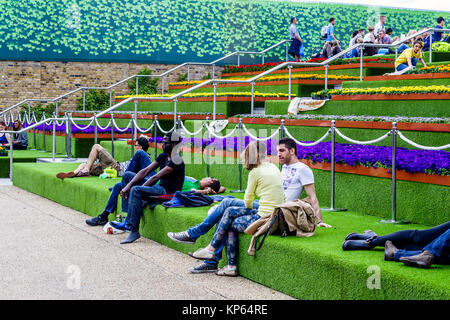 Sonnenanbeter auf die Schritte der Getreidespeicher Square von Regent's Canal in King's Cross, London, UK, geschmückt mit künstlichem Gras und Blumen, 2014 Stockfoto