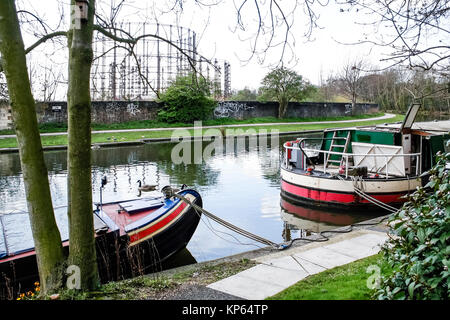 Narrowboats auf der Regent's Canal an Kensal Green, London, UK, die stillgelegte Gasometer im Hintergrund Stockfoto