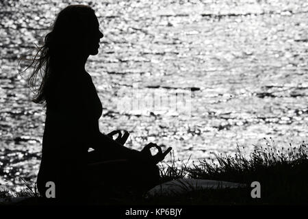 Silhouette einer Frau Yoga bei Sonnenuntergang. Lotus Position. Die französischen Alpen. Frankreich. Stockfoto