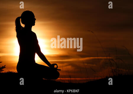 Silhouette einer Frau Yoga gegen das Licht der Abendsonne. Lotus Position. Die französischen Alpen. Frankreich. Stockfoto