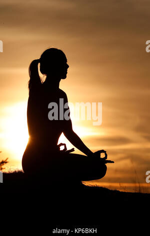 Silhouette einer Frau Yoga gegen das Licht der Abendsonne. Lotus Position. Die französischen Alpen. Frankreich. Stockfoto