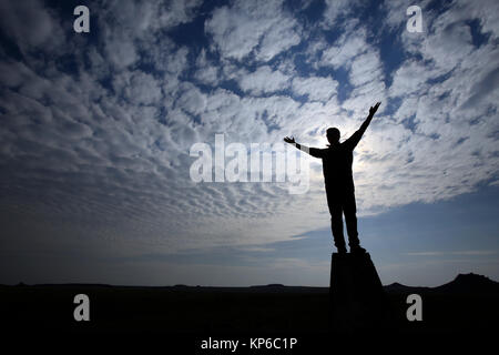 Mann mit erhobenen Armen beten gegen bewölkten Himmel. Silhouette. Stockfoto