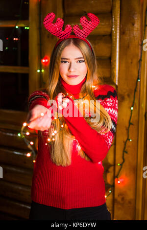 Schöne Mädchen mit festliche Lichter tragende rote Pullover in einem Haus anmelden Stockfoto