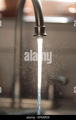 Nahaufnahme von Wassertröpfchen aus flüssigen Strom der Küche Wasserhahn, durch blured Hintergrund isoliert Stockfoto