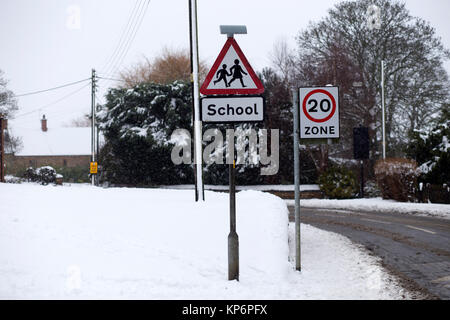 Warnzeichen für eine Schule, und 20 mph Limit Zone im Schnee in Bugbrooke, Northamptonshire Stockfoto