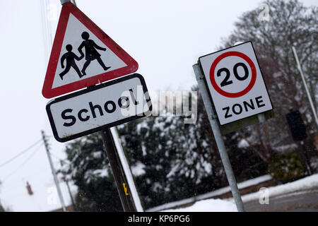 Warnzeichen für eine Schule, und 20 mph Limit Zone im Schnee in Bugbrooke, Northamptonshire Stockfoto