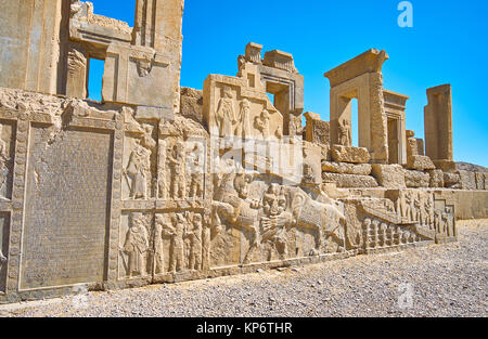 Die Fassade der zerstörten Tachara Palast mit alten persischen Text und Schnitzereien von Soldaten, Höflinge, Löwe beißt der Stier, Persepolis, Iran. Stockfoto