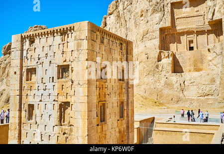 NAQSH-E RUSTAM, IRAN - Oktober 13, 2017: Der rechteckige Ka'ba-ye Zartosht Turm mit Mausoleum von Darius II auf dem Hintergrund, Naqsh-e Rustam Necropo Stockfoto