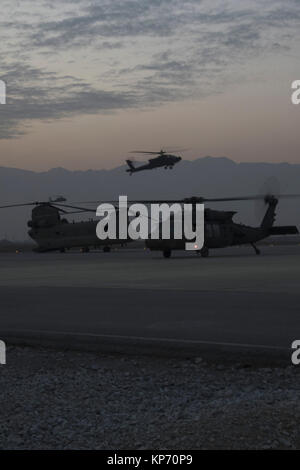 Als die Sonne untergeht, ein AH-64 Apache und UH-60 Black Hawk Hubschrauber Rückkehr von einer Mission im Norden Afghanistans Dezember 9, 2017. Der Hubschrauber und die Crew sind Teil der Task Force Schläger, 4.BATAILLON, 3 Aviation Regiment, aus Savannah, Georgia, unterstützende Funktionen für die Bodentruppen Kommandant in Afghanistan. (US Army Stockfoto