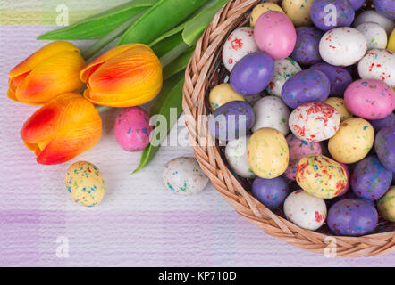 Easter Egg Candy und Tulpen auf einem bunten Tisch Stockfoto