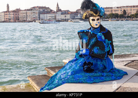 Karneval in Venedig, Venetien, Italien, Frau in hisoric blauen Kostüm und Maske an der Lagune mit Kopie Raum sitzt Stockfoto