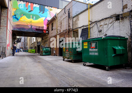 O'Keefe Lane Gasse mit vielen grünen Müll Müllcontainer aufgereiht an der Wand, man rauchen, Graffiti-kunst Stadtbild, Toronto, Ontario, Kanada. Stockfoto