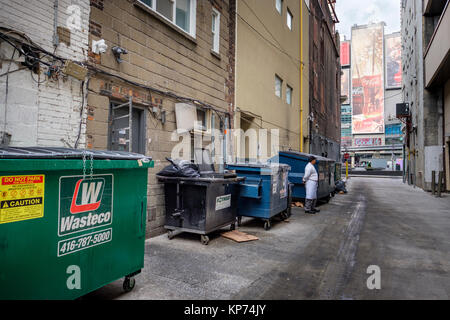 O'Keefe Lane Gasse auf Dundas Square, Müllcontainer Müllcontainer an der Wand aufgereiht, Mann auf Arbeit Unterbrechung, Coca-Cola Anschlagtafeln, Toronto, Ontario, Kanada. Stockfoto