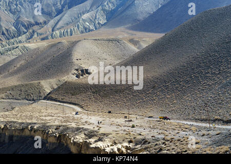 Unbefestigte Straße nach der Kali Gandaki Tal zwischen Kagbeni und Tangbe, Upper Mustang, Nepal. Trekker, Traktoren und Reiter in der Ferne sichtbar. Stockfoto