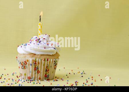 Cupcake garniert mit Sahnehäubchen Kerze und Besprühen Stockfoto