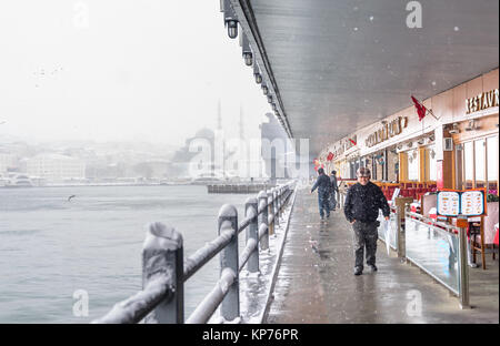 Unbekannter Mann gehen unter der Galatabrücke an einem verschneiten Tag im Winter. Neue Moschee ist auf dem Hintergrund. Istanbul, Türkei, 07. Januar 2017 Stockfoto