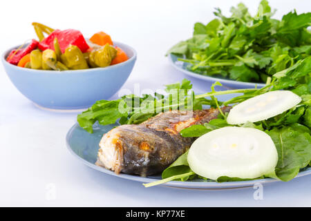 Detaillierte Ansicht von gegrillten Fisch, mit grünem Gemüse und Zwiebeln serviert. Stockfoto