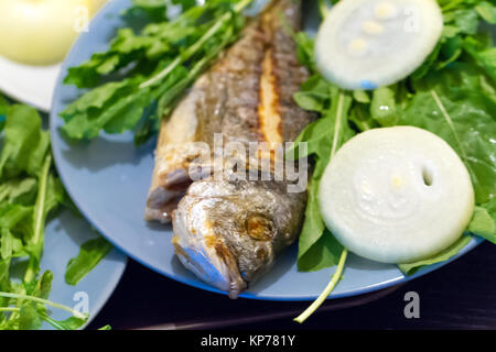 Detaillierte Ansicht von gegrillten Fisch, mit grünem Gemüse und Zwiebeln serviert. Stockfoto