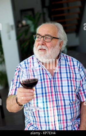 Reifer mann Wein trinken zu Hause Stockfoto