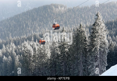 Jasna, Slowakei - Januar 25, 2017: Blick auf zwei orange Kabinen Seilbahn und schneebedeckten Fichten in einem Winter Wald im Skigebiet Jasna, L Stockfoto