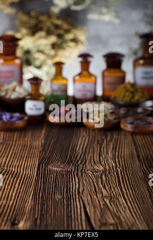 Natürliche Medizin Hintergrund. Messing Mörser, Flaschen und Skala. Rustikale Tabelle. Verschiedene trockene Kräuter in Schalen. Bokeh. Stockfoto