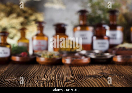 Natürliche Medizin Hintergrund. Messing Mörser, Flaschen und Skala. Rustikale Tabelle. Verschiedene trockene Kräuter in Schalen. Bokeh. Stockfoto