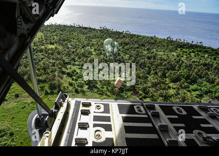 Ein Bündel von Verbrauchsmaterialien ist AIRDROP von der US Air Force C-130 auf der Mikronesischen Insel von Erstmusterprüfungen während der 66th Betrieb Weihnachten Drop 11. Dezember 2017. Jeden Dezember amerikanischen und australischen C-130 Hercules Besatzungen Luftbrücke Essen, Zubehör und Spielzeug Inselbewohner in Mikronesien. Stockfoto