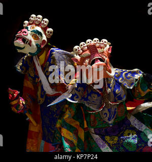 Buddhistische Mönche in rituellen tantrischen Kostüme helle Farben und antiken Masken auf schwarzem Hintergrund. Stockfoto