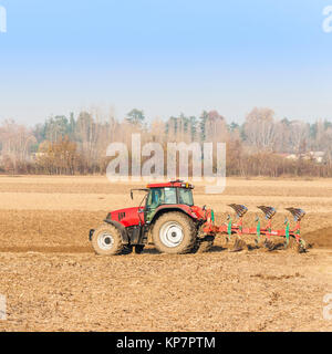 Landwirtschaftliche Arbeit, roter Traktor ein Feld pflügen Stockfoto