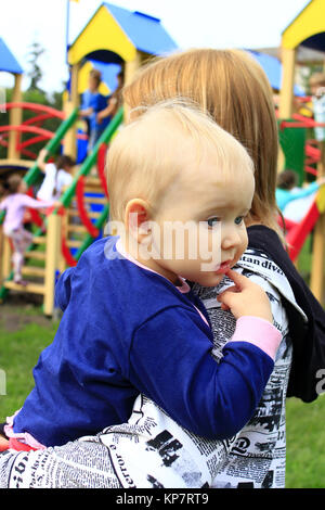 Mutter trägt ihre Tochter auf dem Spielplatz Stockfoto