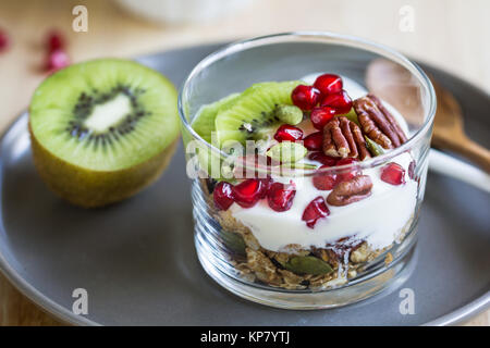 Müsli mit griechischem Joghurt, Kiwi und Granatapfel Stockfoto