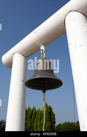 Bronzene Glocke hängen hölzerne Säule auf einem blauen Himmel Stockfoto