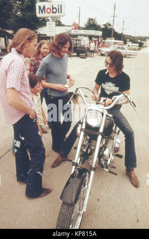 Mann auf Harley Davidson Motorrad hält mit Ihren Freunden und die Zigarette 1970Beleuchtung s Gespräch Stockfoto