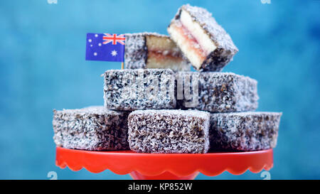 Iconic traditionelle australische Party Food, Lamington Kuchen, auf einem roten, weißen und blauen Hintergrund. Stockfoto