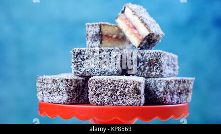 Iconic traditionelle australische Party Food, Lamington Kuchen und Märchen Brot, auf einem roten, weißen und blauen Hintergrund. Stockfoto