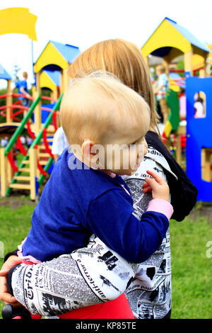 Mutter trägt ihre Tochter auf dem Spielplatz Stockfoto