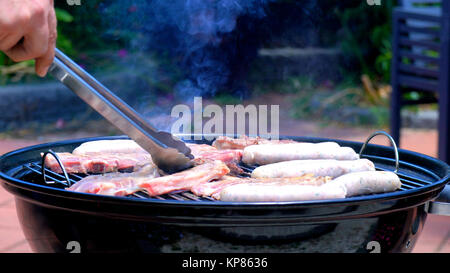 Iconic australisches BBQ Nahaufnahme von Mann kochen Koteletts, sausgaes und Steak, draußen im Garten. Stockfoto