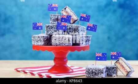 Iconic traditionelle australische Party Food, Lamington Kuchen und Märchen Brot, auf einem roten, weißen und blauen Hintergrund. Stockfoto