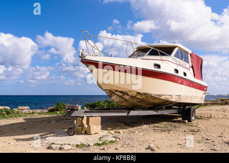 Alte Sunreacher 950 Cabin Cruiser auf einem Anhänger, an einer felsigen Küste geparkt. Stockfoto