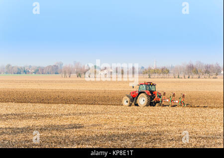 Landwirtschaftliche Arbeit, roter Traktor ein Feld pflügen Stockfoto